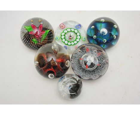 Six unboxed Caithness paperweights comprising a limited edition 'Snowflake', a white miliifiori weight, two single flower bud