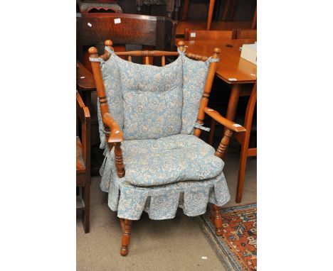 A turned wood chair with blue floral cushion seat and back.