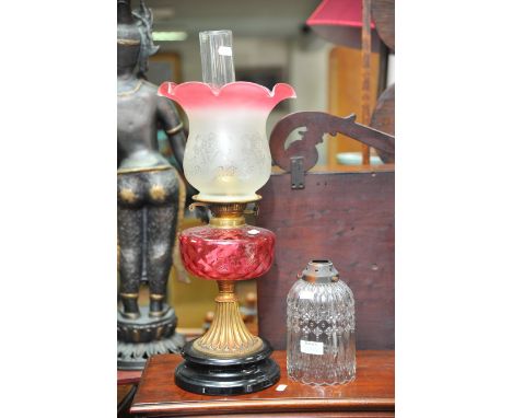 An oil lamp with cranberry glass shade and one other shade