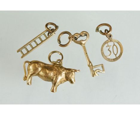 Yellow metal charm modelled as a cow; a 9ct gold charm modelled as a ladder; a 9ct gold charm modelled as a key and a 9ct gol