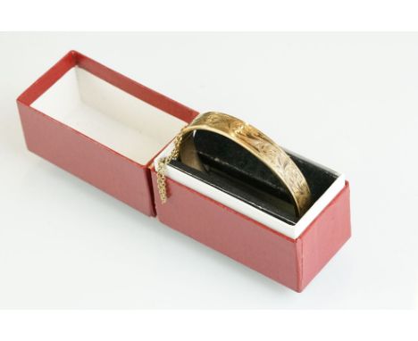 9ct gold hinged bangle, engraved foliate scroll decoration to the upper half, tongue and box clasp with safety chain, hallmar
