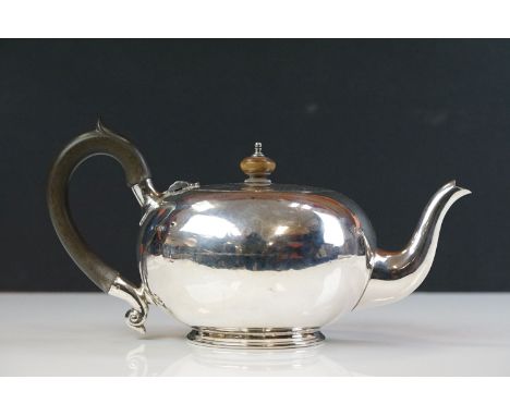 George V silver bachelors teapot of squat plain polished form with scrolling ebonised handle and fruitwood finial, raised on 