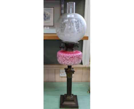 A brass Corinthian column oil lamp with pink glass bowl and etched globe