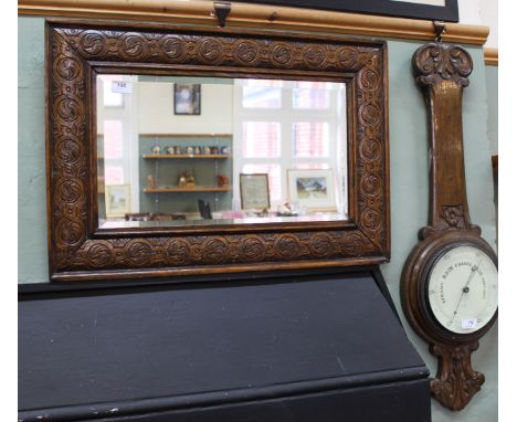 A carved oak wall mirror with bevelled glass plus a carved oak aneroid barometer (as found)