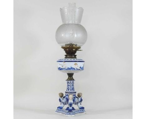 An early 20th century German porcelain oil lamp, with cherub decoration, having an etched glass shade, 60cm high overallCondi