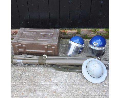A green painted military trunk, 60cm, together with an army helmet, folding stretcher, two police riot helmets (5)