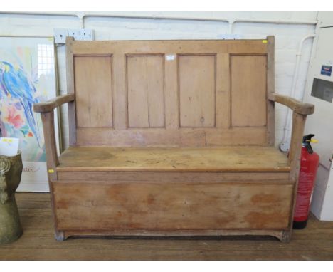 A pine bench with panelled back and hinged seat on a later panelled front 127cm wide