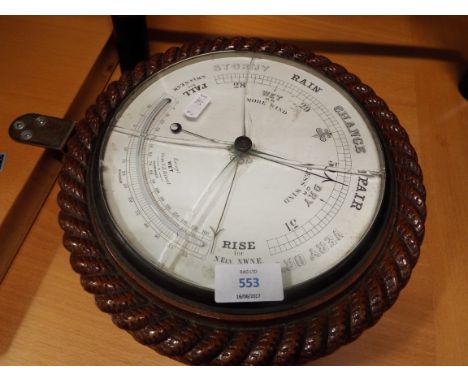 An early 20thC carved oak aneroid barometer with thermometer below