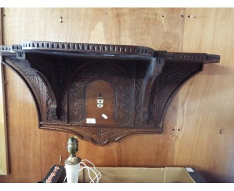 An Arts and Crafts oak shelf with various carved decoration and inlay