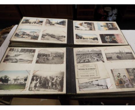 A lacquered postcard album containing a selection of Chinese and Japanese black and white and colour postcards to include pri