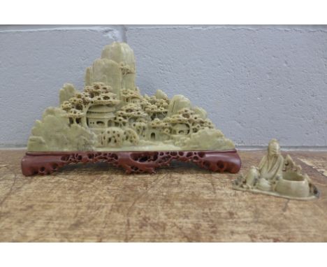 A vintage soapstone carving of temples in a mountain with red soapstone base and a soapstone carving of an elder