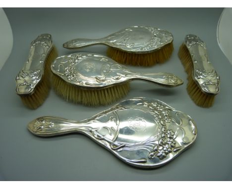 A silver Art Nouveau hand mirror and four brushes, London 1904/5/6, some a/f