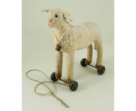 A small Steiff wool plush Lamb on wheels, 1920s, button and white label to left ear, straw filled with black bead eyes, stitc