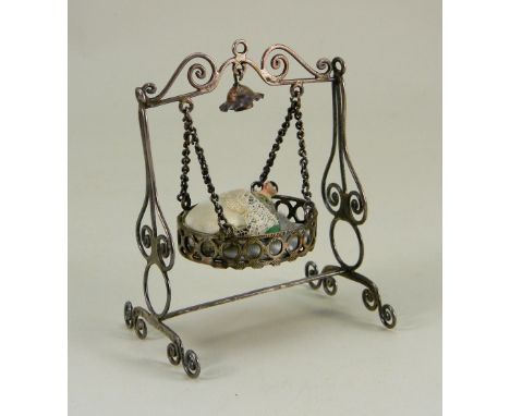 A Silver metal dolls house hanging cradle, continental 19th century, the round crib with pierced sides and pale blue silk bed