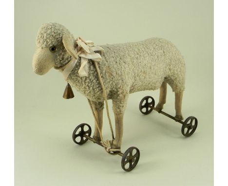 A Steiff wool plush Lamb on wheels, circa 1920, button to left ear, straw filled with felt face, ears and lower legs, green g