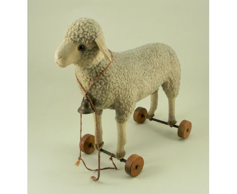 A Steiff wool plush Lamb on wheels, 1920s, button to left ear, straw filled with felt face, ears and lower legs, green glass 