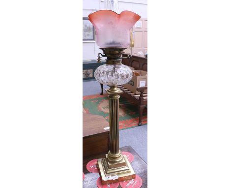 A Victorian Oil Lamp, with etched cranberry tinted shade, cut clear glass reservoir and brass fluted pedestal over a stepped 