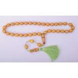 AN ISLAMIC AMBER COLOUR BAKELITE SET OF TASBIH PRAYER BEADS, comprising of 35 oval beads, one shaped