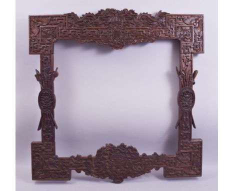 A GOOD LARGE CHINESE CARVED HARDWOOD FRAME, carved with dragons, phoenix, bats and emblems, the central top panel with carved