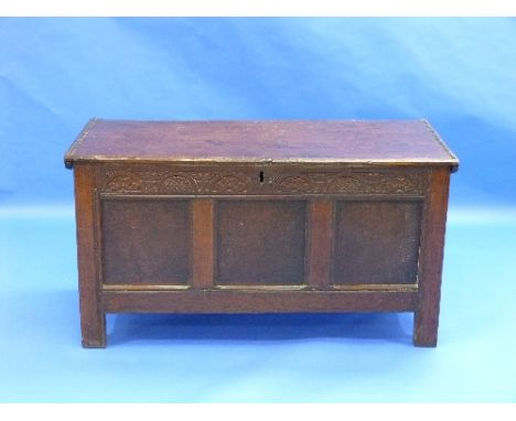 A 17thC oak Coffer, with carved frieze above three panel front and stile legs, 51in (130cm) wide.