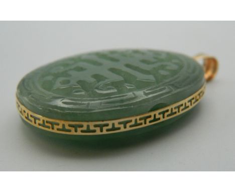 A 14 K gold and carved jade oval pendant. 5 cm high.