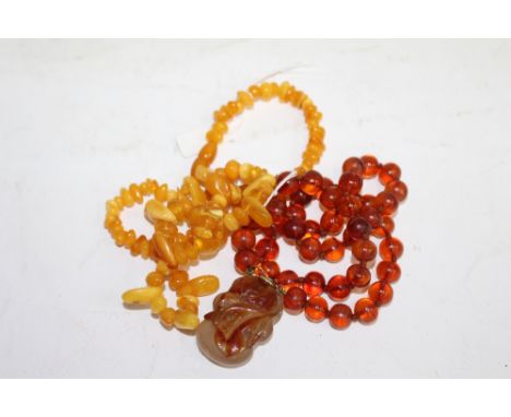 AN ORIENTAL AMBER NECKLACE with a carved jade pebble and a further amber necklace