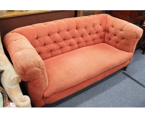 A LATE VICTORIAN CHESTERFIELD TWO SEATER SETTEE with button upholstery and turned mahogany legs terminating on brass castors 