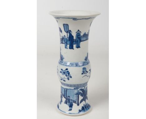 A Chinese blue and white gu shaped vase. Painted in underglaze blue with figures in an outdoor setting. Six character Kangxi 