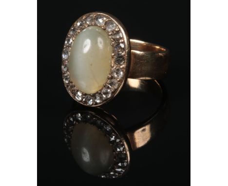 A gold ring with central ovoid cabochon green hardstone under a border of rose cut diamonds (tests as 18 carat gold). 9.1 gra