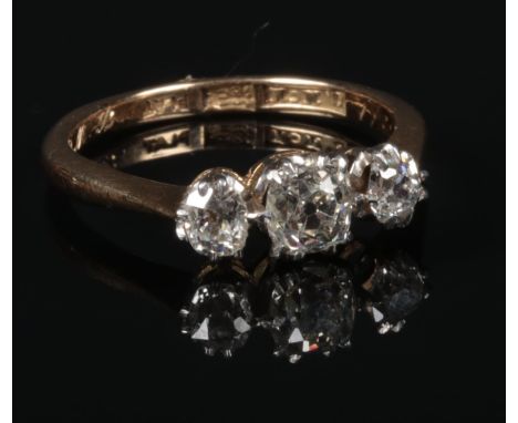 An 18 carat gold and platinum three stone diamond ring. Set with three old European cut diamonds. Principle stone approximate