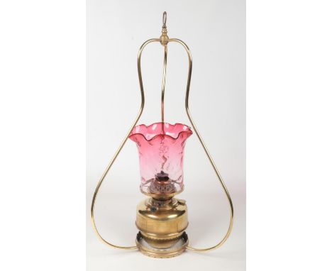 A Victorian hanging brass oil lamp with cranberry glass shade., 83cm.  Glass in good condition. No damage to the metal. Burne