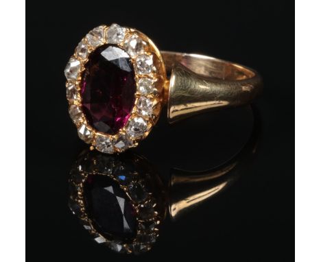 A Victorian 18 carat gold garnet and diamond cluster ring. With a large ovoid faceted purple garnet 10mm x 7mm under a frame 