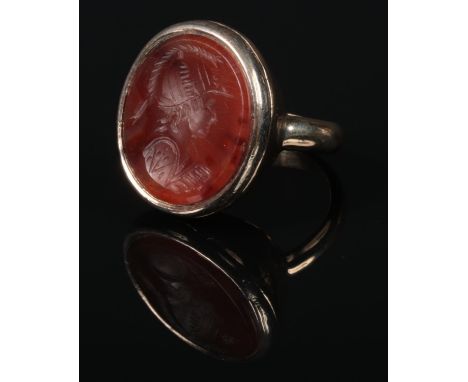 A 19th century yellow metal and carnelian intaglio seal ring. The matrix carved with the profile bush of a Roman soldier, 16.