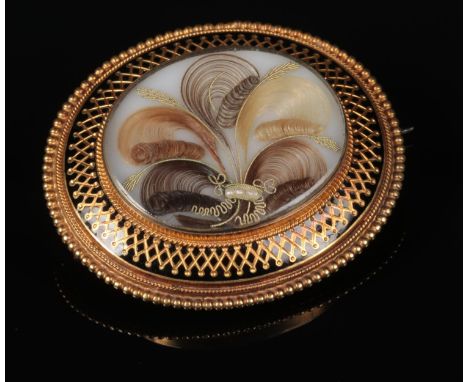 A Victorian cased yellow metal mourning brooch / pendant. With a hairwork, gold thread and seed pearl panel under a black ena