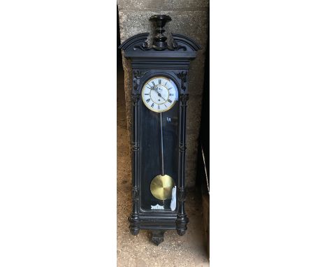 An ebonised wooden cased pendulum wall  clock with enamel face and Roma numerals. Height including pediment 125cms, width 40c