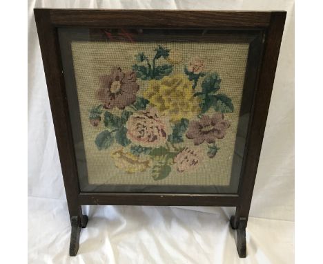An oak framed firescreen with floral wool work panel. 66cms h x 53cms w.Condition ReportGood condition.