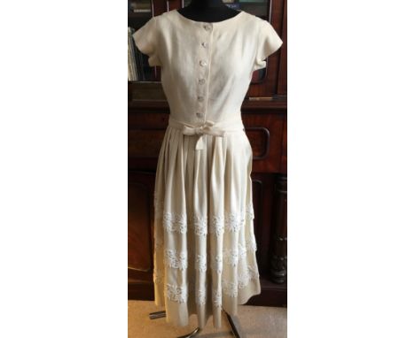 A Traina Norell of New York cream linen 1950's dress with gathered shirt to waist and belt, applique white trim to shirt and 