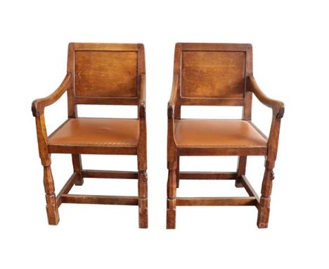 Workshop of Robert Mouseman Thompson (Kilburn): A Pair of English Oak Panel-Back Armchairs, brown leather seats, on octagonal