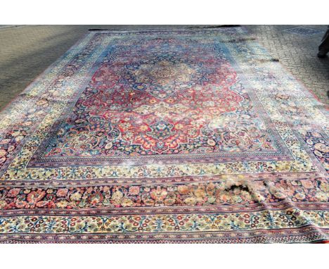 A LARGE PERSIAN MESHED CARPET, red ground within a triple row border, all over stylised floral decoration (worn, moth damage)