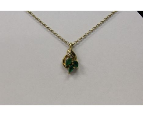 A THREE STONE EMERALD AND DIAMOND PENDANT on a 9ct fine yellow chain.