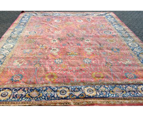 A PERSIAN TABRIZ CARPET, pink ground within a single blue ground border, with stylised floral decoration. 13ft 7ins x 11ft 2i
