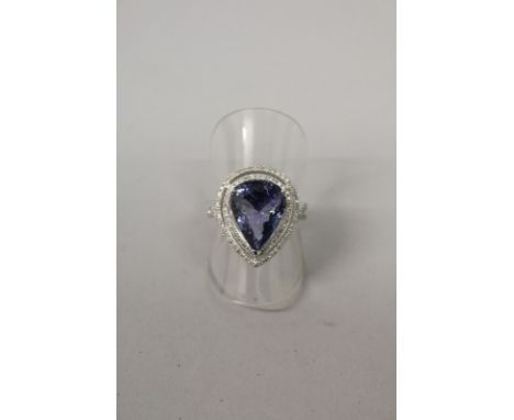 A GOOD PEAR SHAPED CUT TANZANITE RING, approx 5.5cts, with two rows of small diamonds and diamond crossover shoulders all set