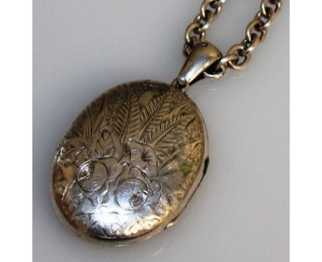A VICTORIAN ENGRAVED SILVER OVAL LOCKET with long silver chain.