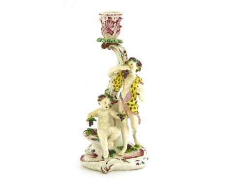 A Bow candlestick group representing autumn, c.1760, the holder supported on a scroll with two figures, each holding bunches 