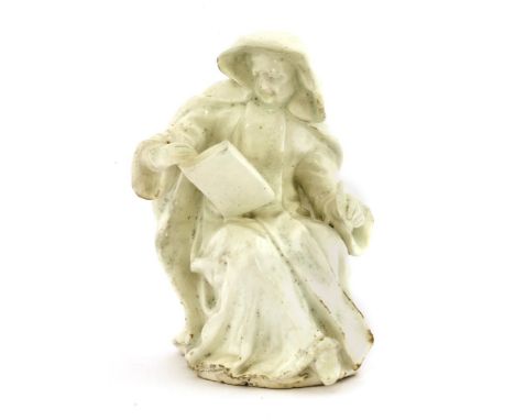 A Bow white-glazed seated nun, c.1755, wearing a long hooded coat, holding a quill and open book, 15.3cm high