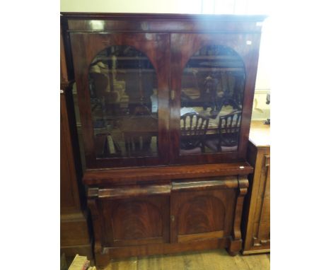 A mahogany bookcase on cupboard, with two arch glazed doors above two drawers and two panel doors, 125 cm wide