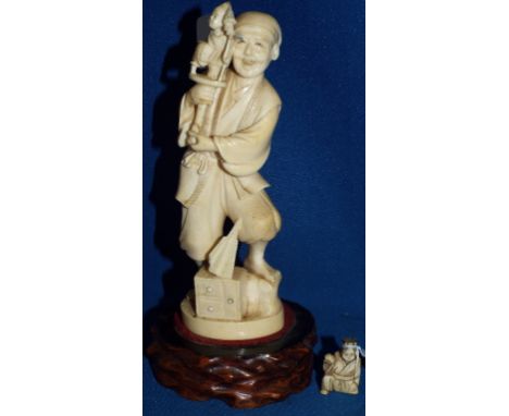 A Japanese carved ivory group, of a man holding a pole and a child, signed on a red lacquer tablet, Meiji period (some damage