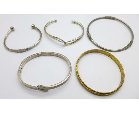 Four silver bangles and a gilt coloured bangle 