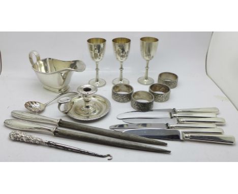 Three small plated goblets with crossed kukri emblem, a plated chamber stick, four napkin rings, a plated sauce boat, etc. 