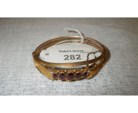 A 9ct yellow gold bangle set with five graduated garnets